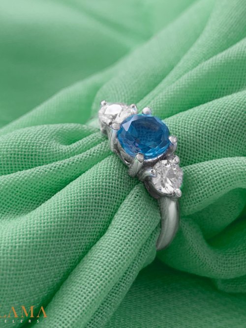 Crafted in sterling silver, this ring is set with a hand picked round blue topaz, framed by two American diamonds. Main Stone Blue Topaz Stone American Diamonds